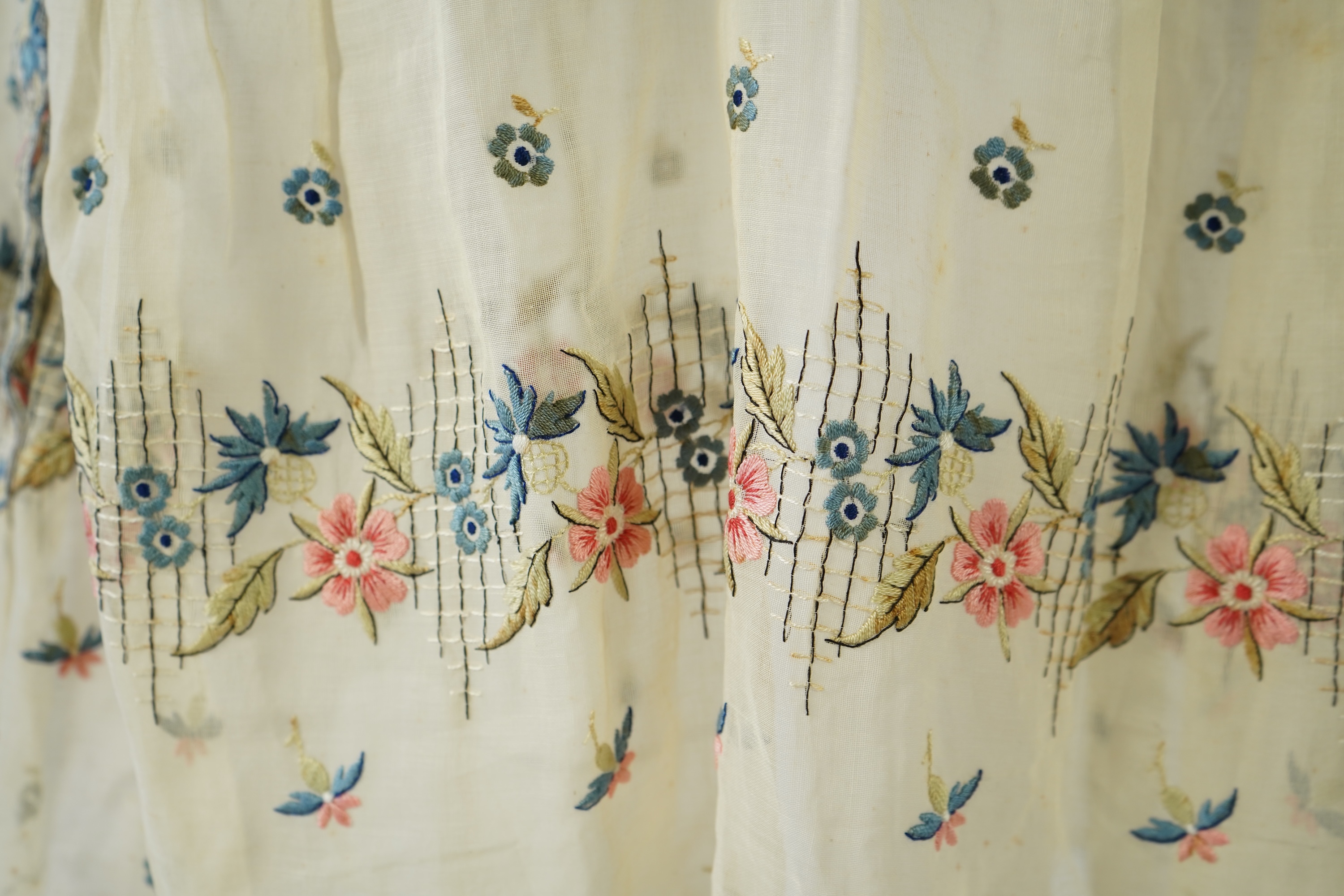 An unusual 1920's fine cream lawn summer dress with hand embroidered blue, pink, flowers, tie and picot edging., 116cm long. Condition - some small rust stains and one small tear at the back right shoulder.